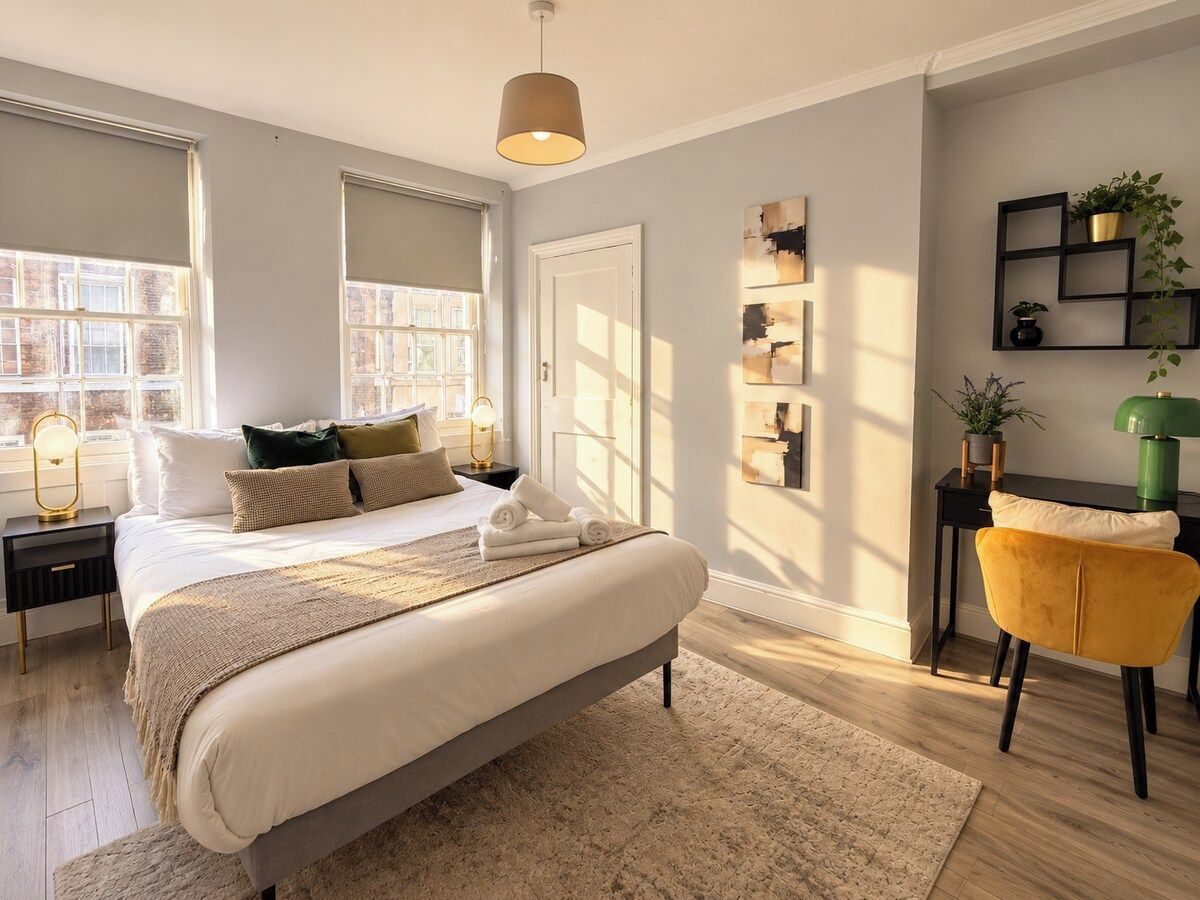 A bedroom with a bed, bedside tables, a chair, and a window.