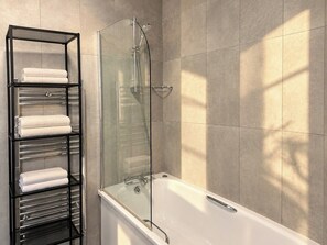 A bathroom with a glass-enclosed shower, a white bathtub, and a black metal towel rack with folded towels. - Soho Hideaway | Private Room near West End (Greater London)
