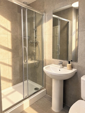A modern bathroom with a glass-enclosed shower, a pedestal sink, and a toilet. - Cosy Soho Room near Piccadilly & Chinatown (Greater London)