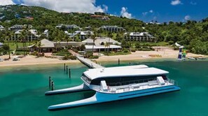 A waterfront property with a large boat docked, a beach, and houses in the background. - Westin St. John Coral Vista Studio - Full Resort Access - Spring Break/Easter (Cruz Bay)