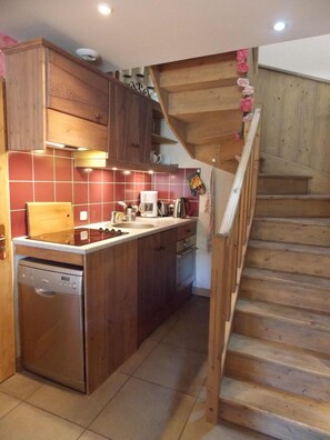 A kitchen with wooden cabinets, a built-in dishwasher, and a wooden staircase. - 180m from ski slopes, Ground floor, balcony, fireplace or stove, parking, ski locker, 65m², Valloire (Valloire)