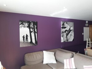 A living room with a purple wall, a beige sofa, and two black-and-white photographs. - 180m from ski slopes, Ground floor, balcony, fireplace or stove, parking, ski locker, 65m², Valloire (Valloire)