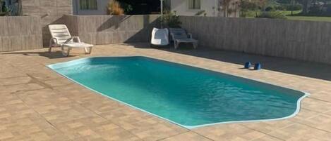 A swimming pool with lounge chairs and a building in the background.