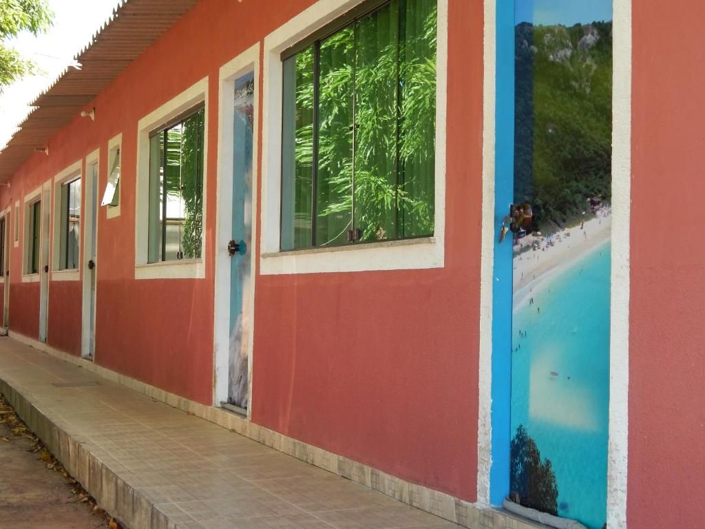 Ein Gebäude mit roter Außenfassade, mehreren Fenstern und einer Tür mit einem Wandbild einer Strandansicht.