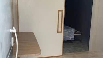 Una habitación con armario correderas, una cama con colcha estampada y suelo de baldosas.