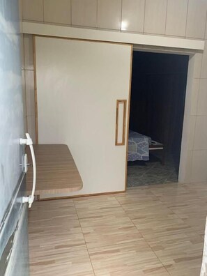 Una habitación con armario correderas, una cama con colcha estampada y suelo de baldosas.