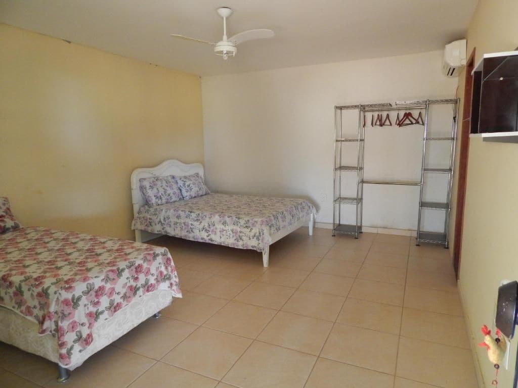 A bedroom with two beds, a ceiling fan, a wardrobe, and a wall-mounted heater.