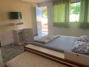 A bedroom with a bed, a TV mounted on the wall, a wardrobe, and a window with curtains. - Sítio Bom Retiro (São Pedro da Aldeia)