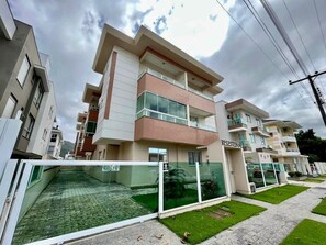 A modern multi-story residential building with balconies, a gated entrance, and a well-maintained lawn. - Comfortable apartment on Palmas beach. (Governador Celso Ramos)