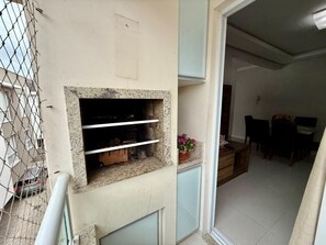 Ein Balkon mit Kamin aus Stein, eine Essecke mit Stühlen und Tisch sowie ein Blumentopf.
