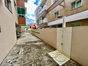 A narrow corridor with a tiled floor, a yellow hose on the ground, and a sign reading 'RESERVATION'. - Comfortable apartment on Palmas beach. (Governador Celso Ramos)