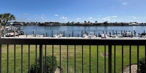 A marina with boats docked, a grassy area in the foreground, and a clear sky. - Wake up to Clam Bay from this light- filled 2 bed 2 bath condo in South Seas Club on Marco Island (Marco Island)