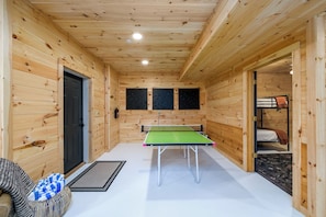 Un interior de madera con mesa de ping pong, una puerta y una cama litera.