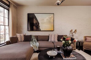 Un salon moderne avec un grand canapé, une table basse et un tableau accroché au mur.