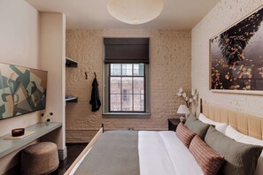 A bedroom with a large bed, a window, a painting, and a wall-mounted shelf. - Newly Renovated CBD Condo, Near French Quarter (New Orleans)