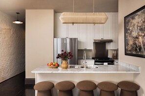 A modern kitchen with a marble countertop, stainless steel appliances, and a hanging light fixture. - Newly Renovated CBD Condo, Near French Quarter (New Orleans)