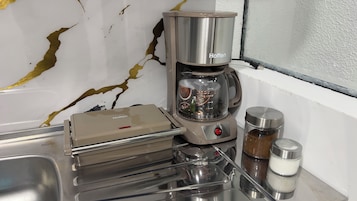 A kitchen with a coffee maker, a toaster, and a container of sugar.