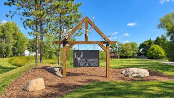 A wooden sign with a deer head logo and the text 'Northwoods Antler Lodge' mounted on a simple wooden structure.