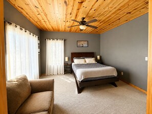 Spacious bedroom with a comfortable bed and sitting area gives guests extra room to relax and settle in. - Northwoods House | Sleeps 12 | ATV Trail (Birchwood)