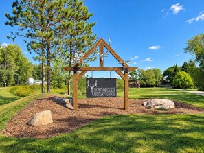 A wooden sign with a deer head logo and the text 'Northwoods Antler Lodge' mounted on a simple wooden structure.