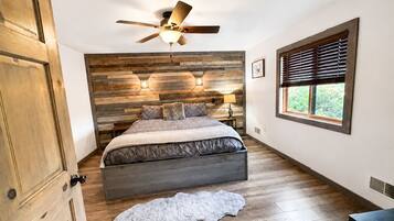 Comfortable private bedroom with warm wood accents, ceiling fan, natural light, and a relaxing Northwoods atmosphere for unwinding after a full day of Wisconsin adventures.