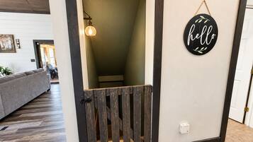 A doorway leading to a stairwell with a wooden gate, a wall-mounted light fixture, and a 'hello' sign.