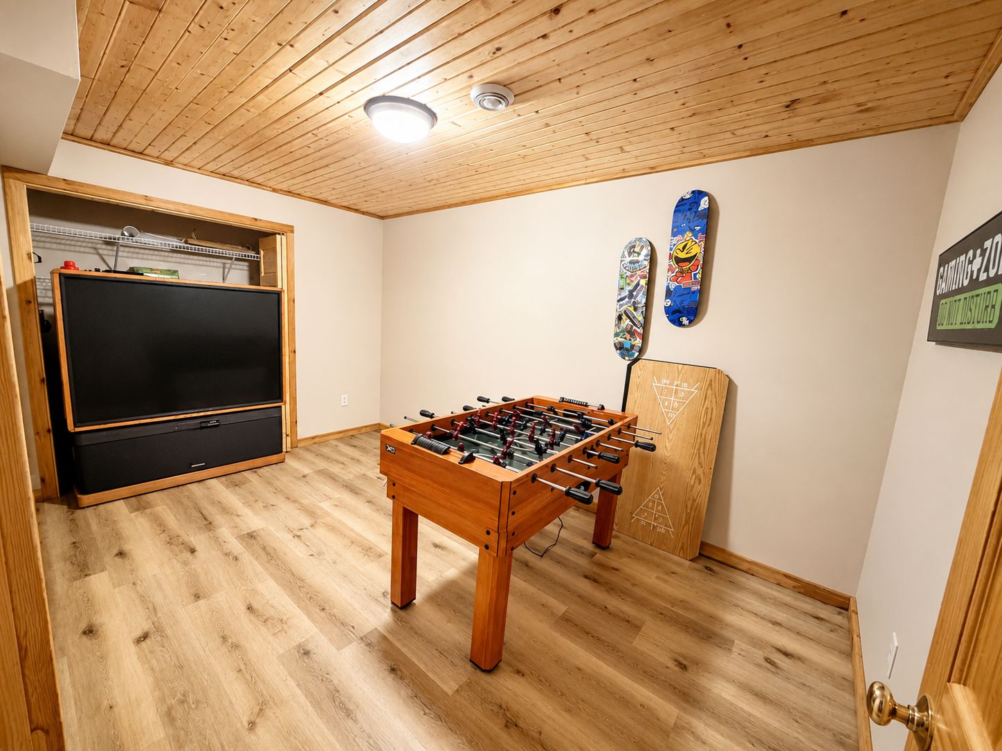 Una habitación con techo de madera, mesa de fútbol de mesa, televisor y zona de juegos.
