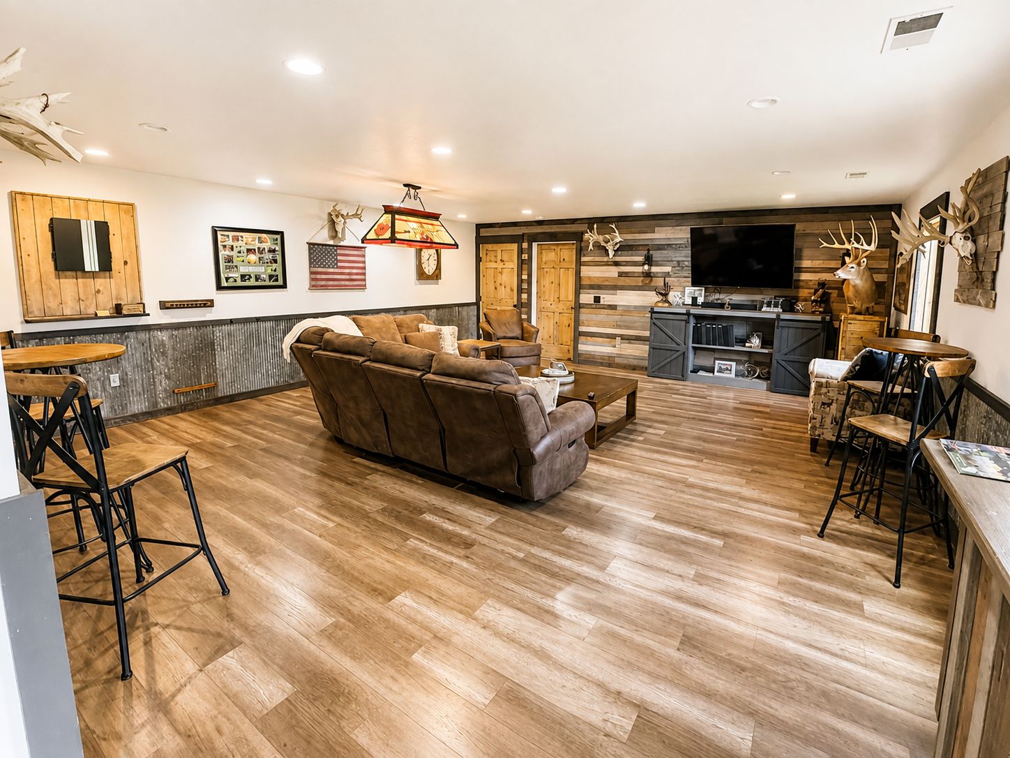Una sala de estar moderna con sofá, un comedor con barra y una cocina con televisor.