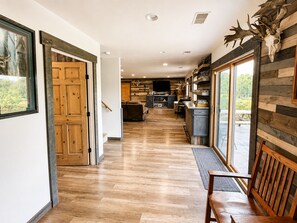 A hallway with wooden flooring, a bench, and a door leading to a living area.
