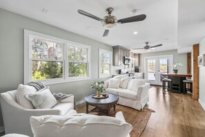 A spacious living room with a sofa set, a coffee table, and a dining area with bar stools. - Lakeside Villa (Santa Rosa Beach)