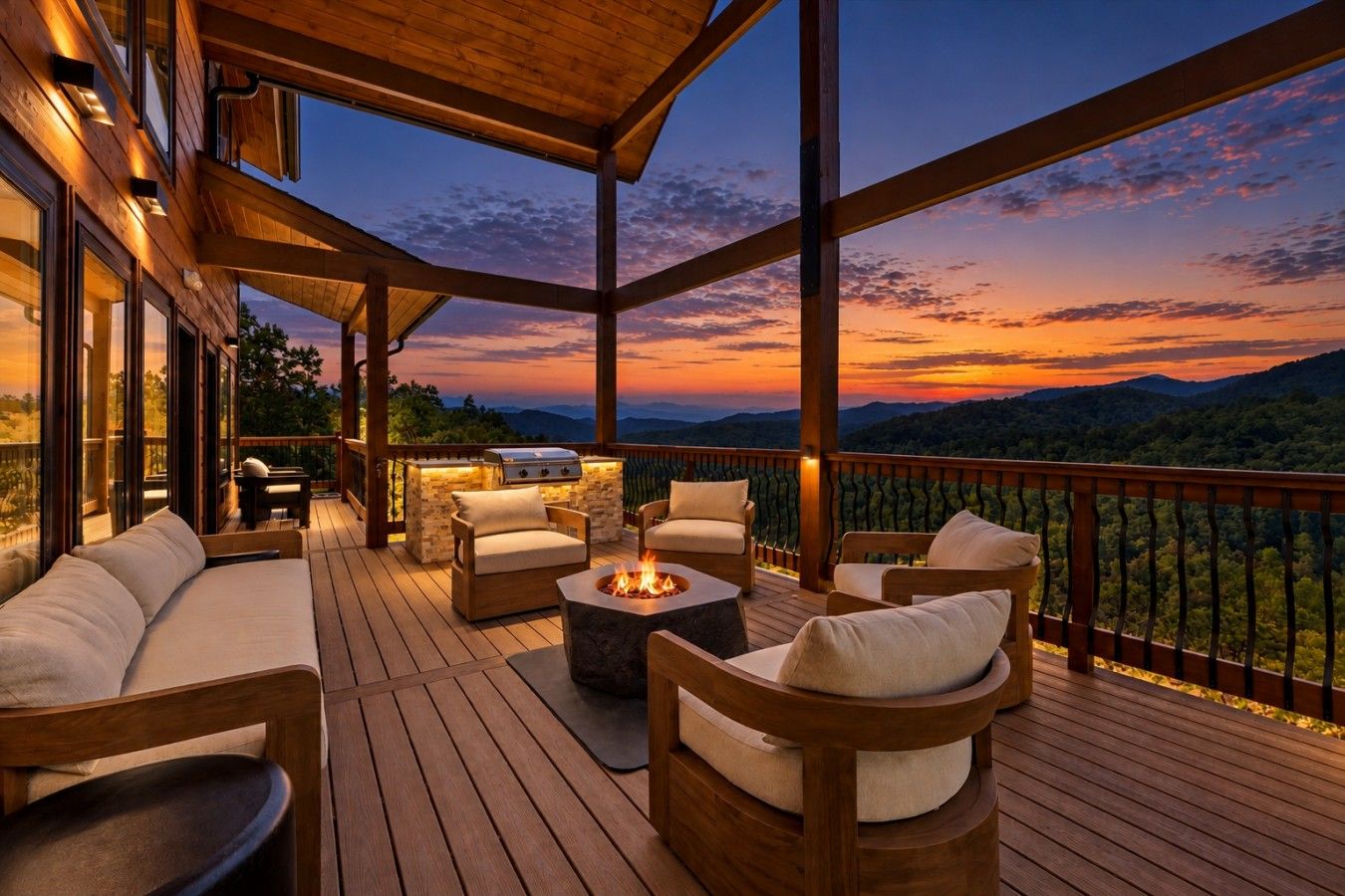 A wooden deck with outdoor seating and a fire pit, overlooking a mountainous landscape at sunset.