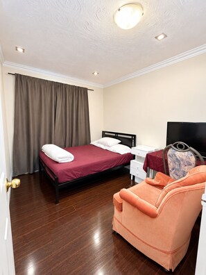 Ein Hotelzimmer mit Bett, Fernseher, Schreibtisch und Stuhl.