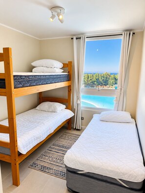 A room with bunk beds, a view of the sea, and a ceiling light fixture.