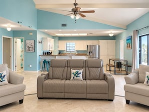 A spacious living area with a beige sofa set, a ceiling fan, and a kitchen in the background. - Isla Bella - Waterfront Retreat, Dock, Boat Lift (Port Isabel)