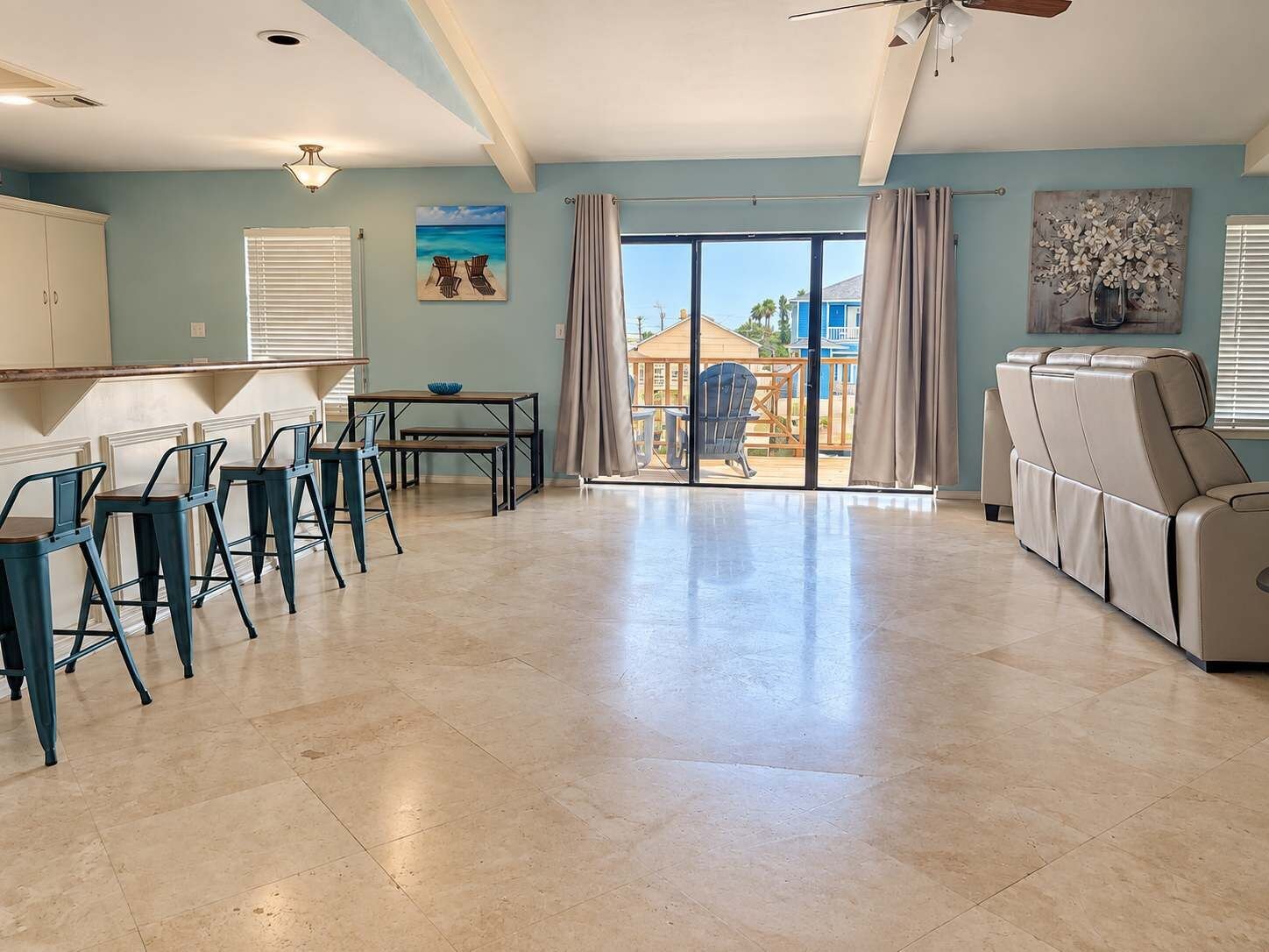 A spacious living area with a dining set, a sofa, and a view of the outdoors.
