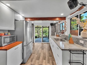 A modern kitchen with a built-in refrigerator, a microwave, and a sink. - Honolii Hale - Oceanfront (Hilo)