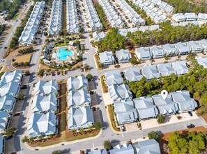 An aerial view of a residential area with multiple houses, a swimming pool, and a clear road network. - The Good Life (Santa Rosa Beach)