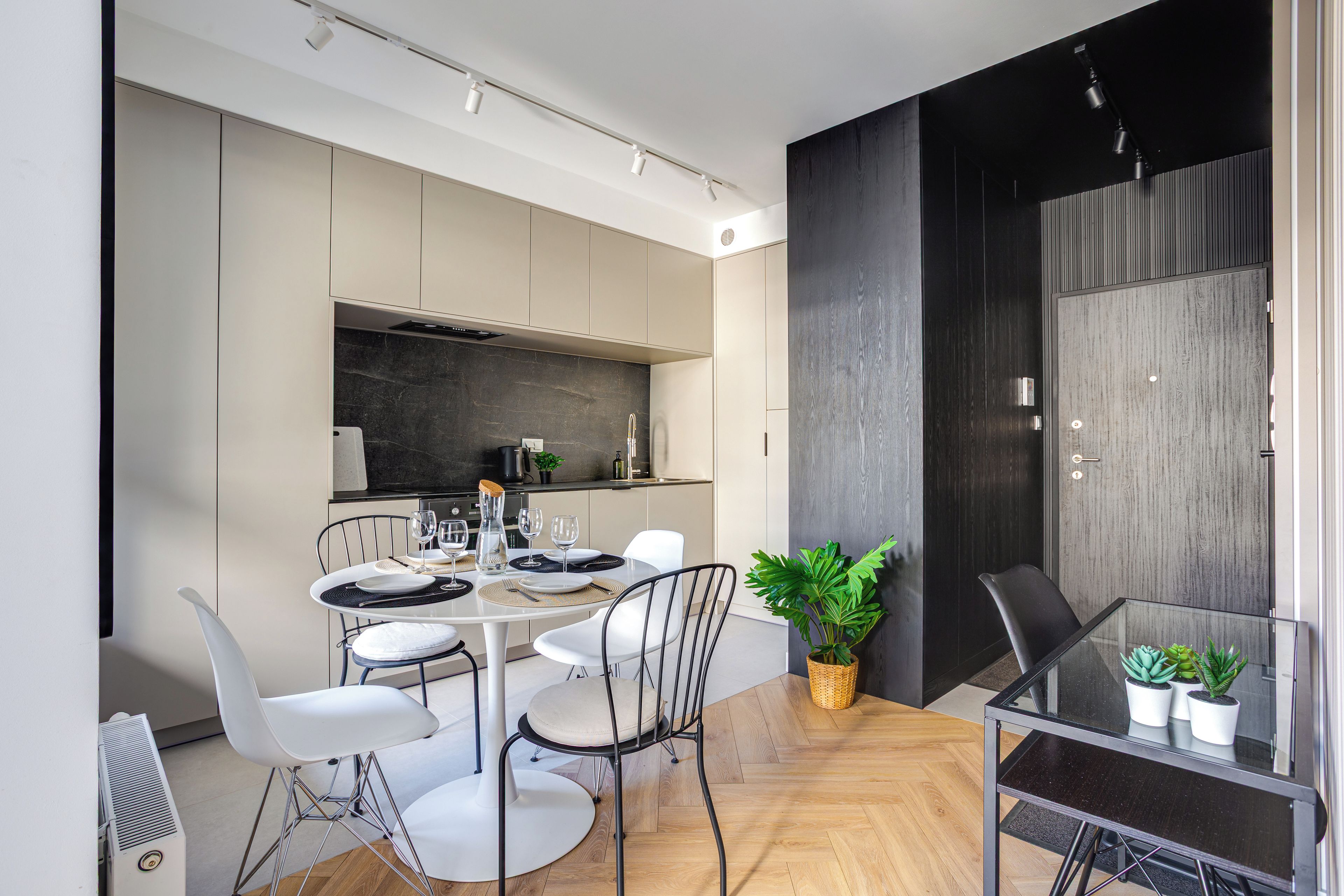 A modern dining area with a round table, white chairs, and a glass-top table.