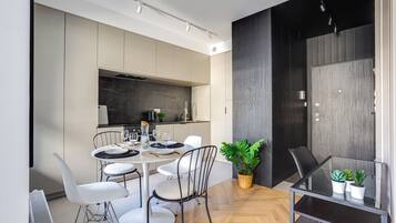 A modern dining area with a round table, white chairs, and a glass-top table.