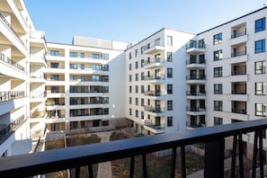 Un edificio residencial de varios pisos con balcones, un patio interior y cielo despejado.