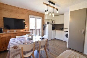 A compact kitchen with a dining area, a flat-screen TV, and a wooden ceiling. - 350m from ski slopes, 1st floor, balcony, tv, ski locker, 26m², Valloire (Valloire)