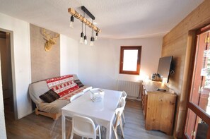 A cozy room with a sofa, a dining table, chairs, a wooden cabinet, a television, and a decorative wall piece. - 350m from ski slopes, 1st floor, balcony, tv, ski locker, 26m², Valloire (Valloire)