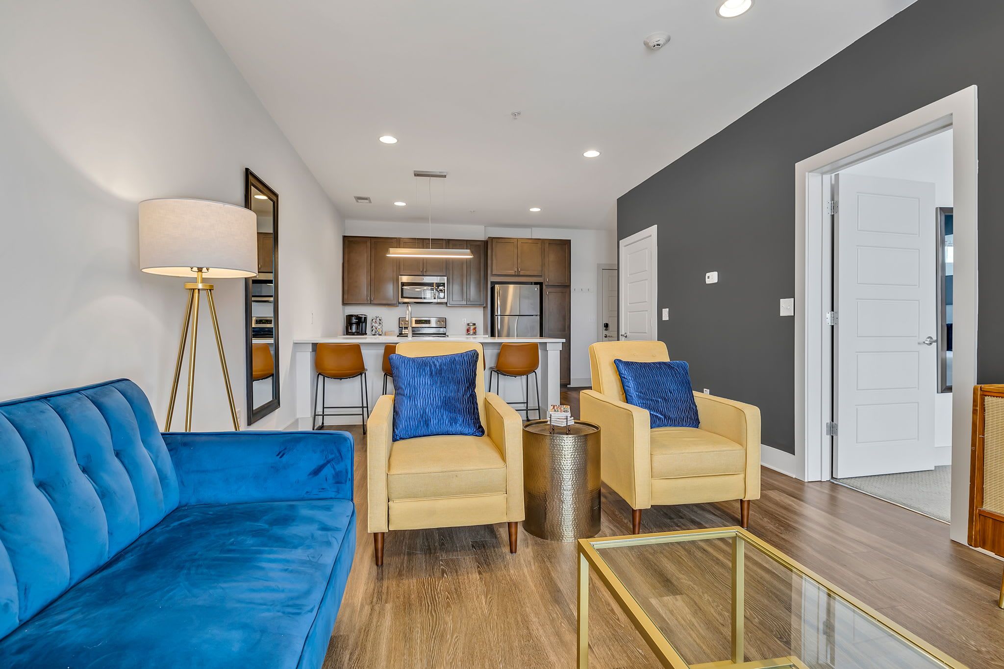 A modern living room with a blue sofa, two yellow armchairs, and a floor lamp.