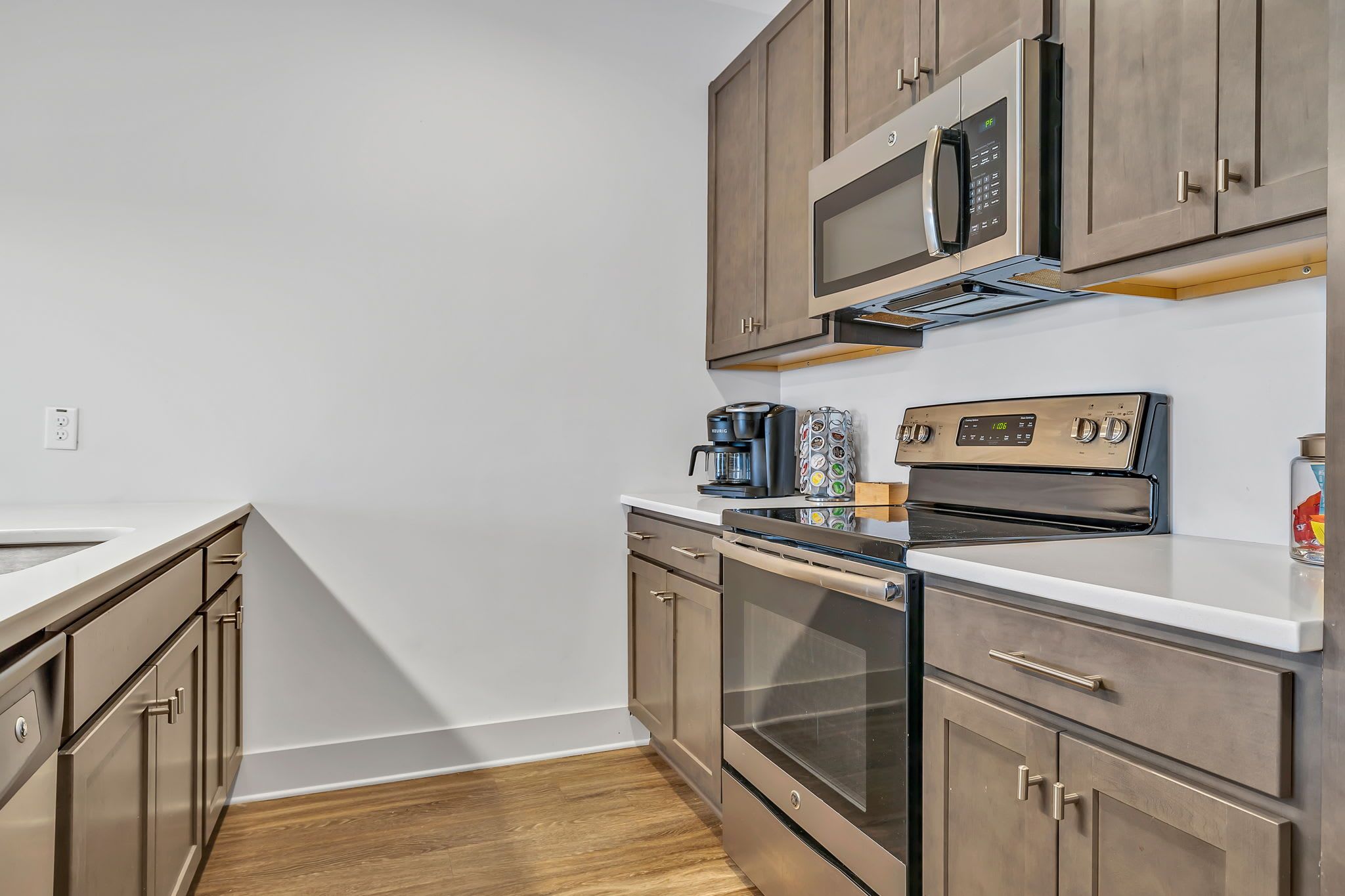 A modern kitchen with stainless steel appliances, wooden cabinets, and a white countertop.