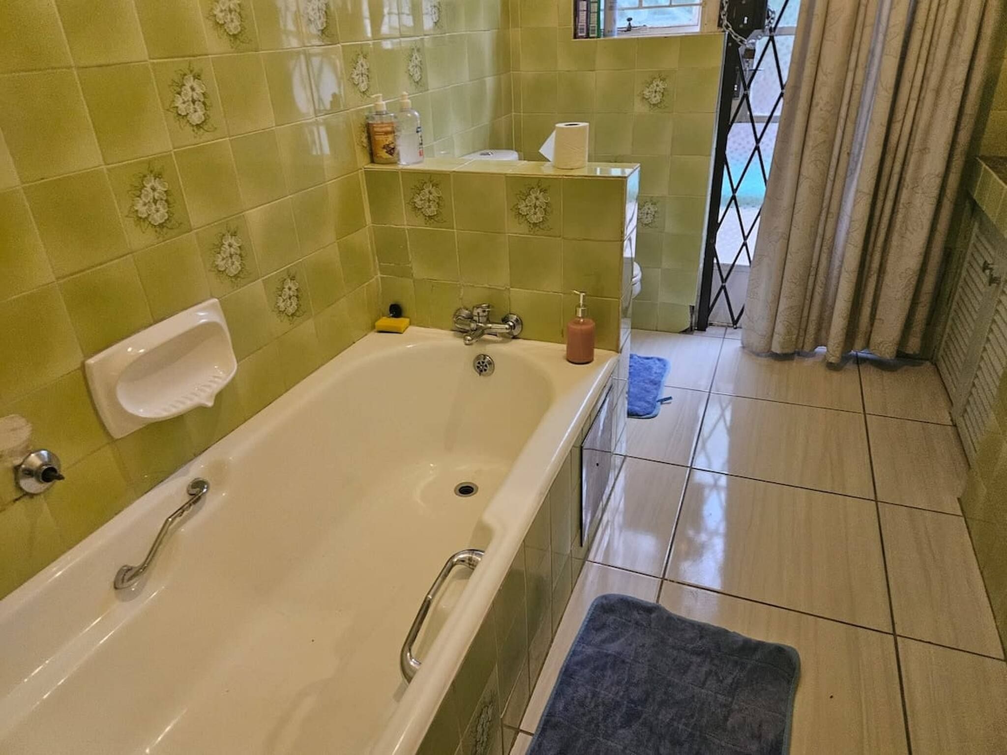 A bathroom with a bathtub, a toilet, and a sink. There is a towel rack and a shelf with toiletries.