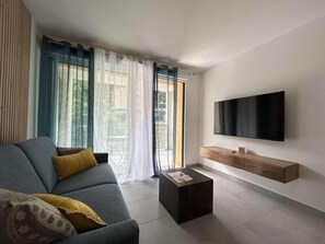 A modern living room with a sofa, coffee table, and a flat-screen TV mounted on the wall. - 300m from ski slopes, 2nd floor, terrace, tv, ski locker, 58m², Serre Chevalier (Briançon)