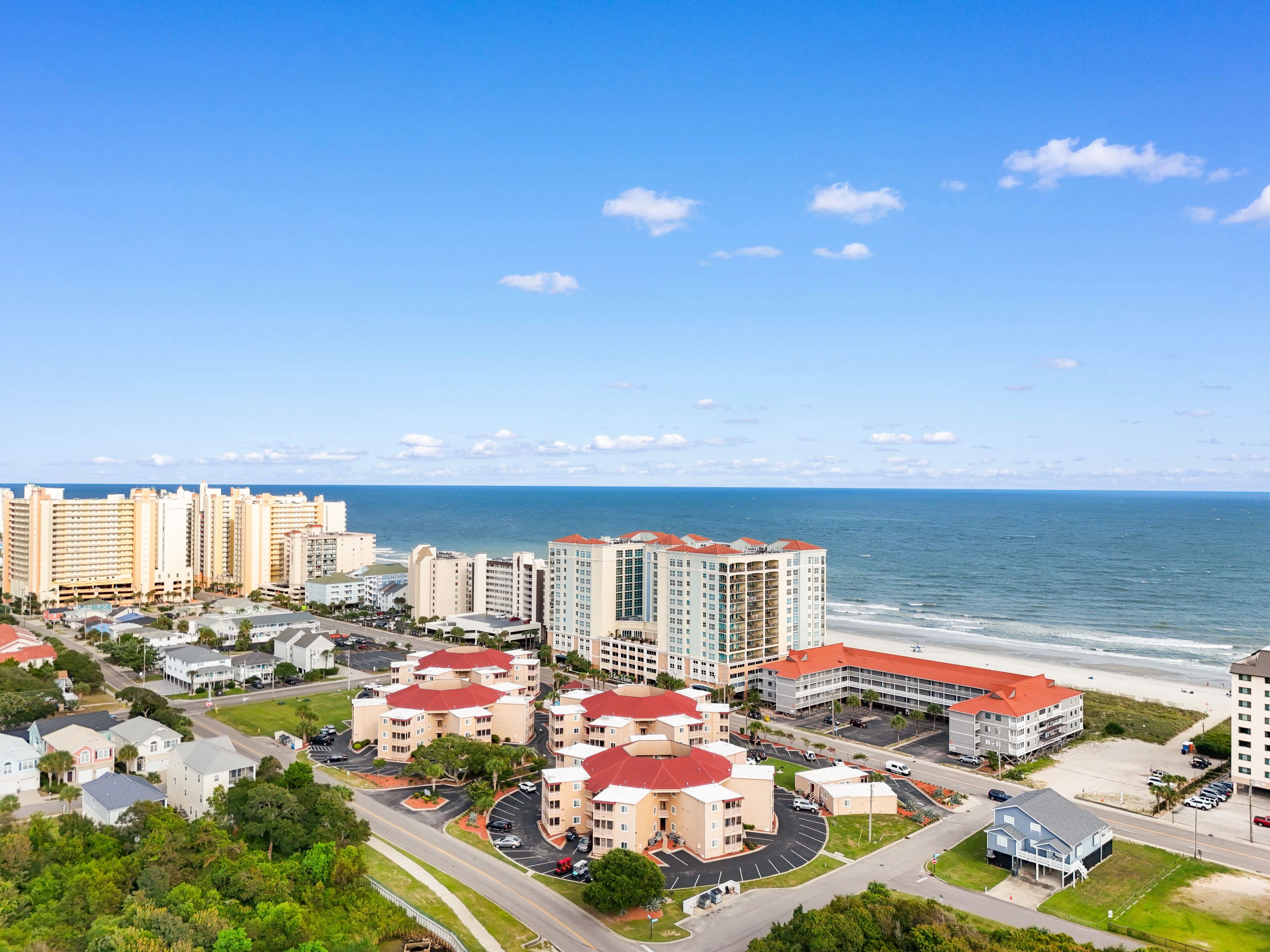 Zona residencial costera con varios edificios de apartamentos, una playa y cielo despejado.