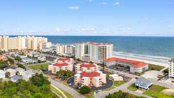 Zona residencial costera con varios edificios de apartamentos, una playa y cielo despejado.