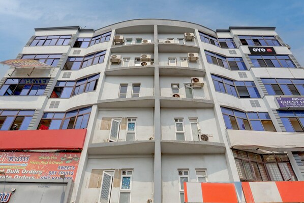 A multi-story hotel with balconies, air conditioning units, and signage for a hotel and a guest house. - Deluxe Room Anusuya Hotel (Bhubaneshwar)