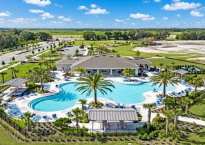 Ett semesterhotell med en stor pool, solstolar och en huvudbyggnad.